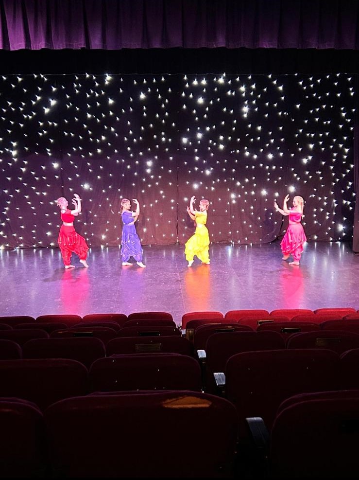 Acro students demonstrating flexibility on stage